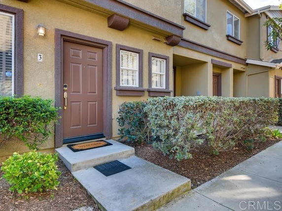 Front view of a townhouse with a brown door and small front steps.