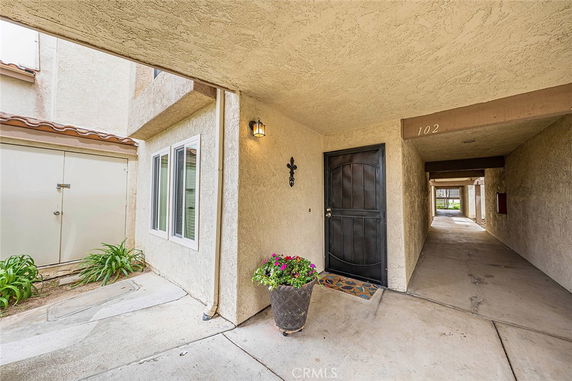 Front view of an apartment entrance with a dark wood door and exterior light fixture.