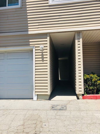 Front view of a building with a garage and a narrow passageway.