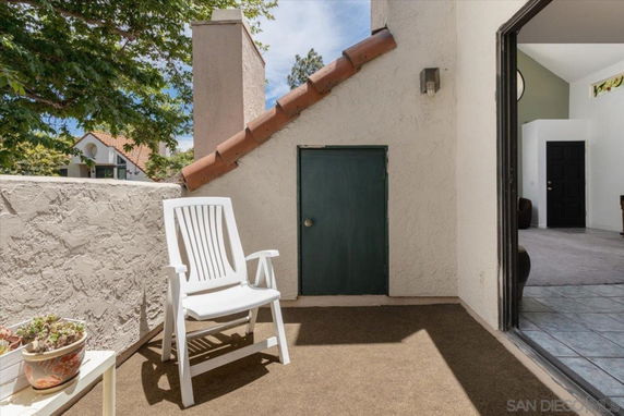 Rooftop area with a white chair and a small door, partially enclosed by a low wall.