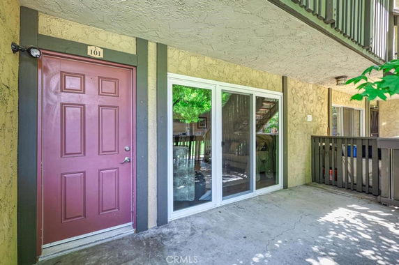 Front view of a building entrance with a red door and sliding glass doors.
