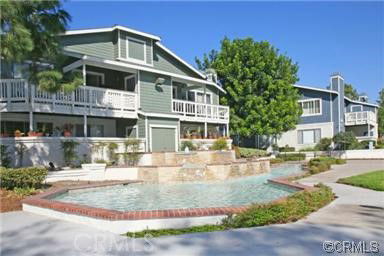 Front view of two-story houses with balconies and a water feature in the front.