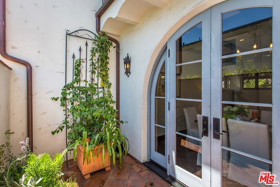 Exterior view of a house with arched French doors and potted plants.