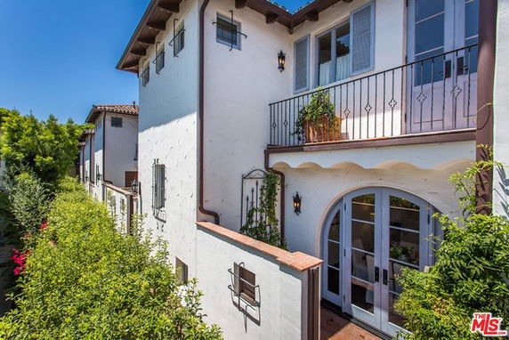 Front view of a multi-story house with balconies and arched doors.