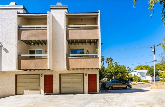 Front view of a residential building with two balconies and attached garages.