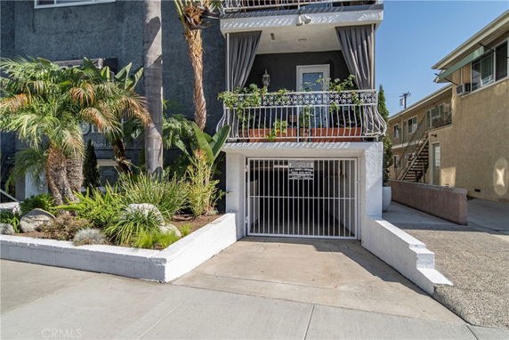 Front view of a multi-story building with a gated garage entrance.