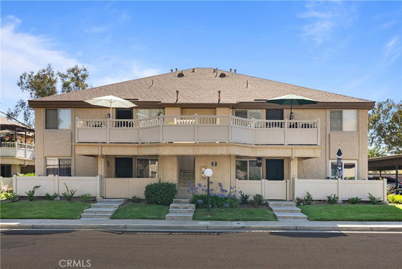 Front view of a two-story residential building with a balcony and umbrellas.