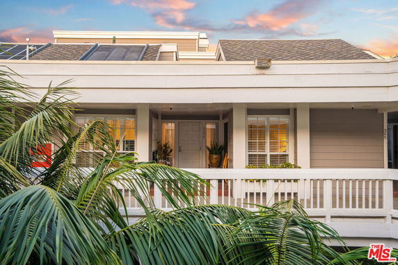 Front view of a house with a porch and solar panels on the roof.