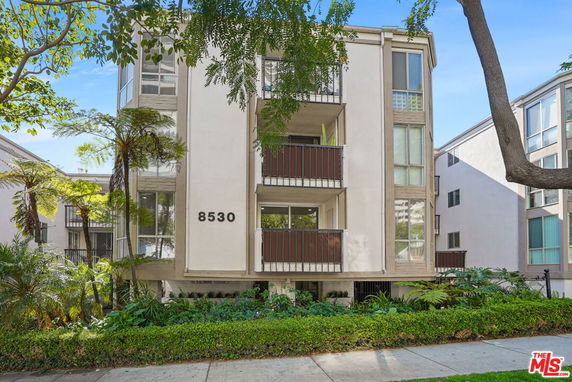 Front view of a three-story apartment building with balconies and large windows.
