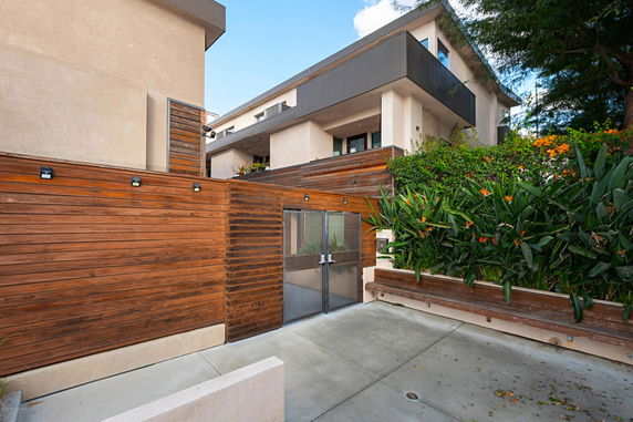 Front view of a modern multi-story building with wooden and glass elements.
