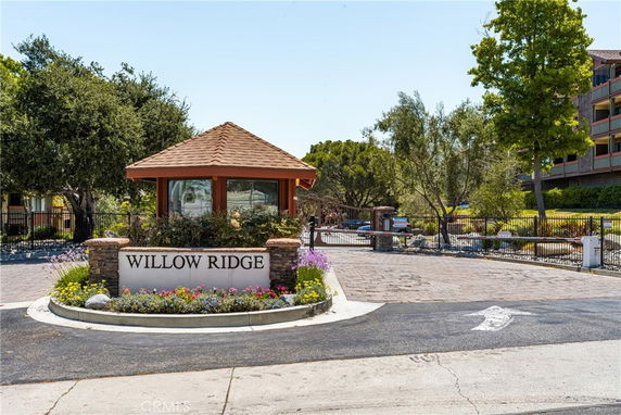Entrance view of a property with a sign reading 'Willow Ridge' and a small building with a tiled roof.