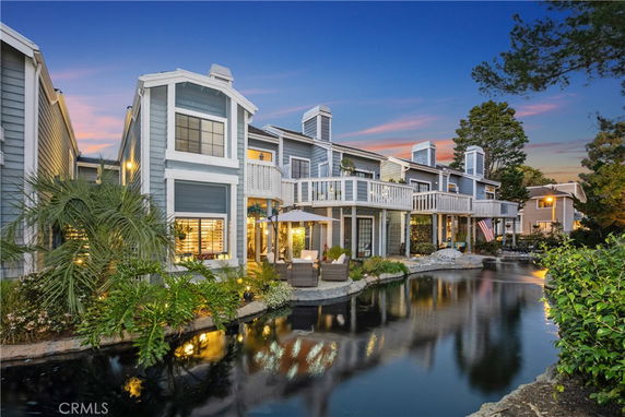 Front view of a two-story house with balconies and water feature in front.