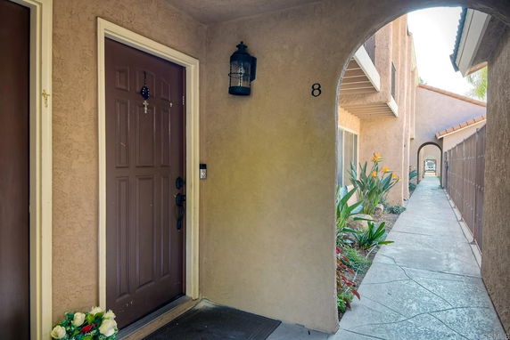 Exterior corridor of a residential building with a brown front door labeled number 8.