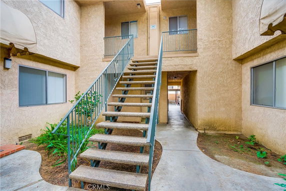 Front view of a building with a central staircase leading to upper-level apartments.