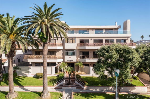 Front view of a multi-story building with balconies and palm trees.