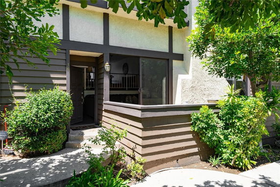 Front view of a two-story house with a partially enclosed entry area and wooden paneling.