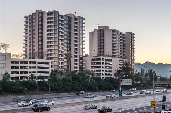 Front view of a multi-story residential building with adjacent parking structures.