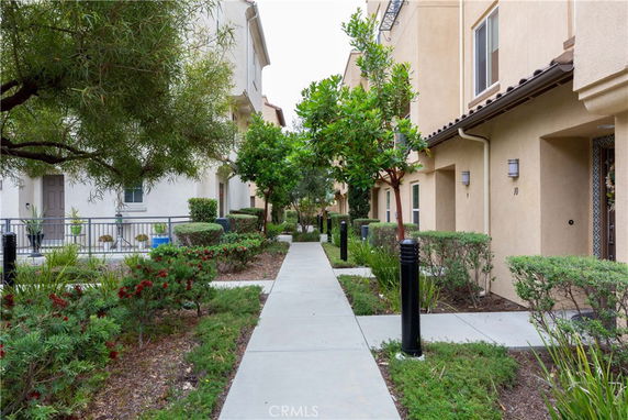 Front view of townhouses with a walkway and landscaped garden.