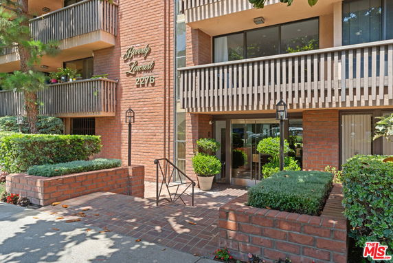 Front view of a multi-story brick building with balconies and entrance.