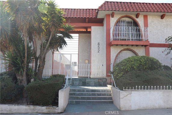 Front view of a two-story house with a red tiled roof and decorative balcony.