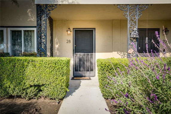 Front view of a house with decorative wrought iron columns and a screen door.