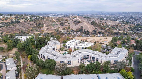 Panoramic view of a large residential complex with hilly terrain in the background.