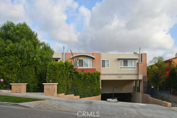 Front view of a two-story building with a gated entrance and greenery on the sides.