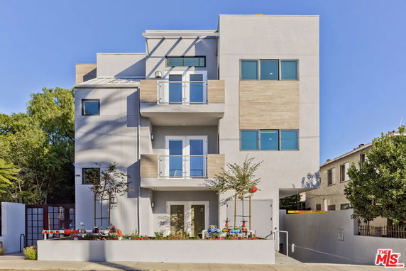 Front view of a modern, multi-story building with balconies and large windows.