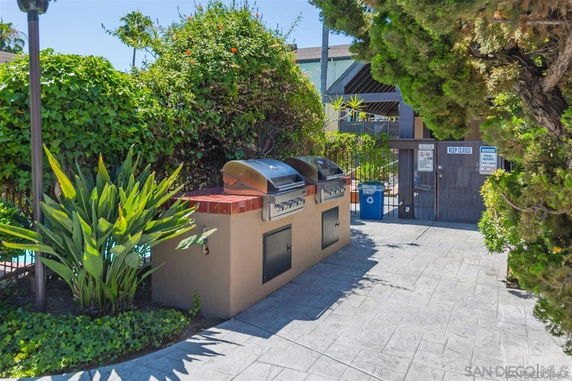 Outdoor area with two barbecue grills surrounded by greenery.