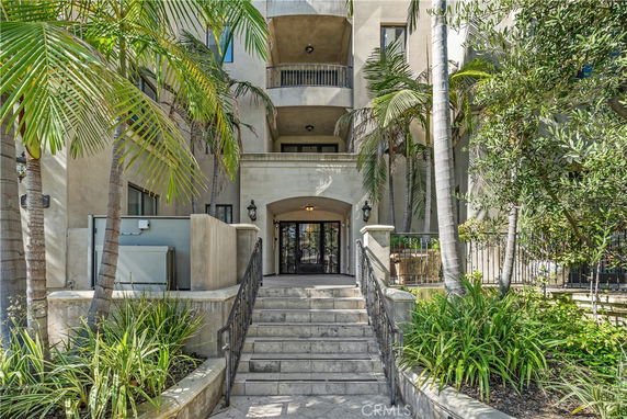 Front view of a multi-story building with stairs leading to the entrance.