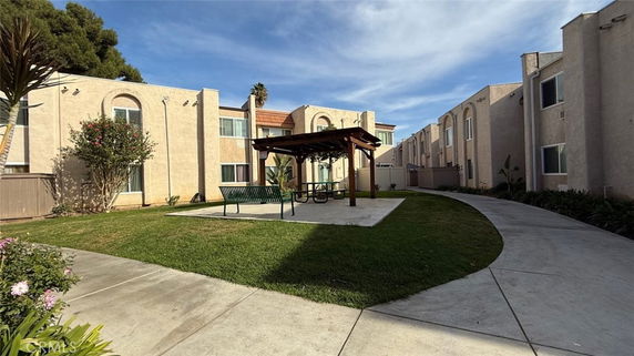 Front view of a two-story building complex with a central walkway and shaded seating area.