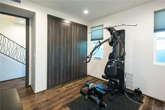 Room with a multi-gym fitness machine and wooden flooring.