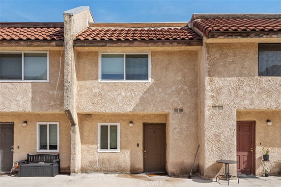 Front view of a multi-story building with brown doors and beige stucco exterior.