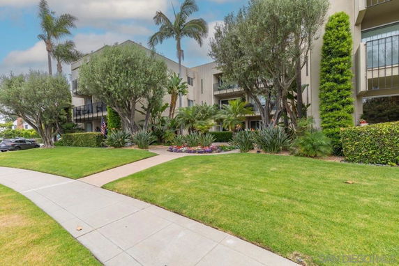 Front view of a multi-story residential building with balconies and lush landscaping.
