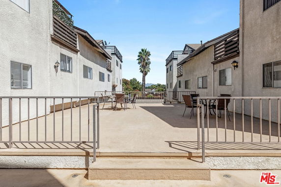 Open rooftop area between two residential buildings, featuring outdoor seating and railing.