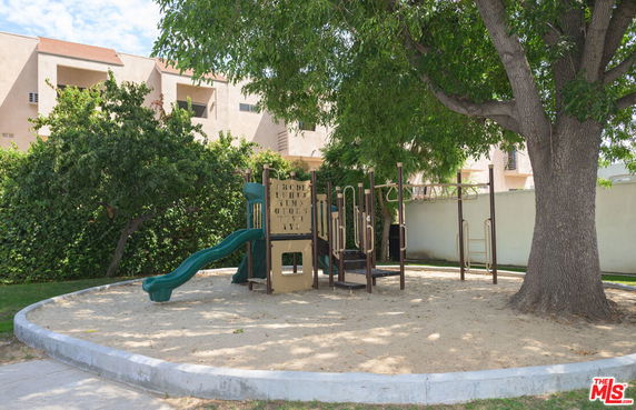 Outdoor play area with playground equipment and trees.