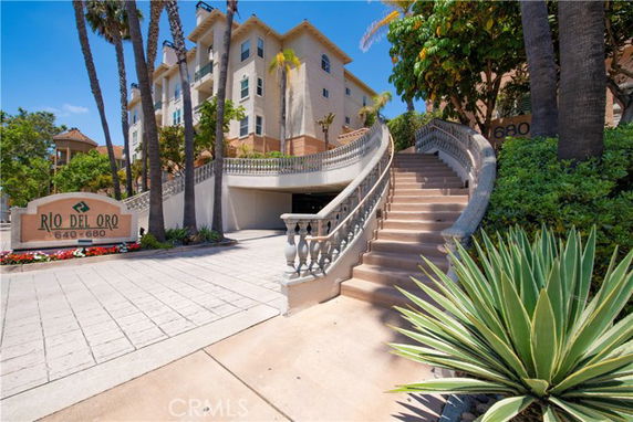 Front view of a multi-story building with a curved staircase and driveway entrance.