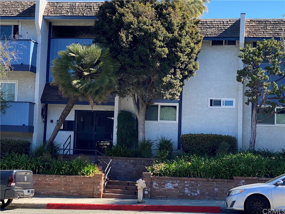 Front view of a multi-story house with a shingle roof and balcony.