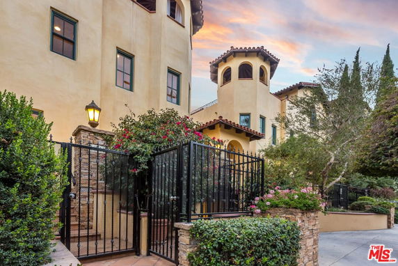 Front view of a multi-story house with a tower-like structure and gated entrance.