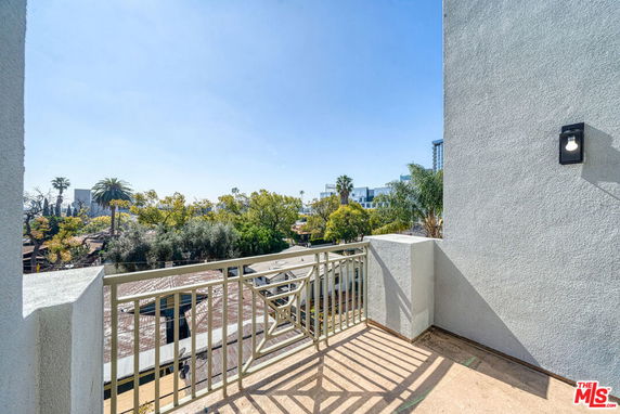 View from a balcony with railings extending over surrounding rooftops and trees.
