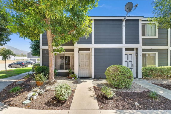 Front view of a townhouse with a dark exterior and white trim, featuring a pathway leading to the entrance.