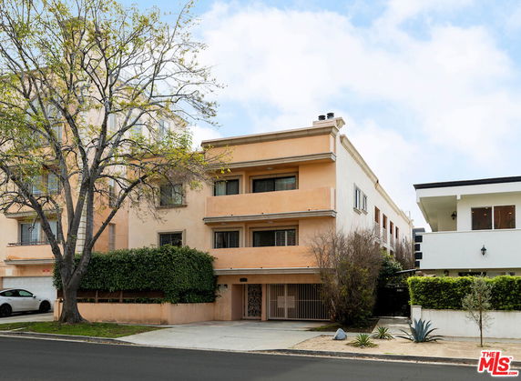 Front view of a multi-story building with balconies and a gated entrance.