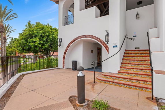 Front view of a building with arched entryways and decorative outdoor stairs.