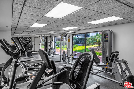 Indoor gym area with exercise equipment and large windows.