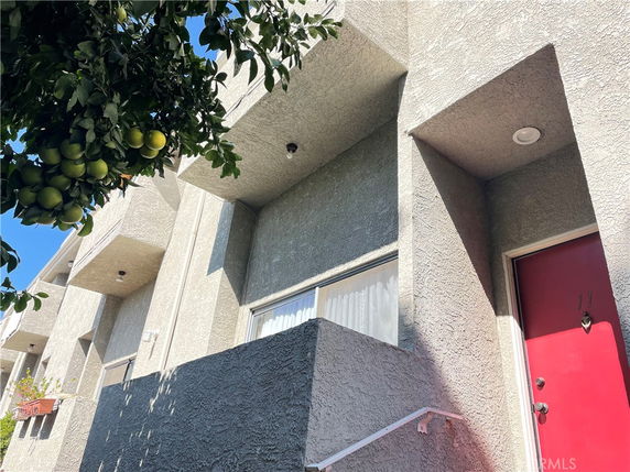 Front view of a multi-story building with red doors and textured exterior walls.