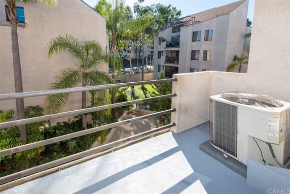 Rooftop area with an air conditioning unit, overlooking adjacent apartment buildings.