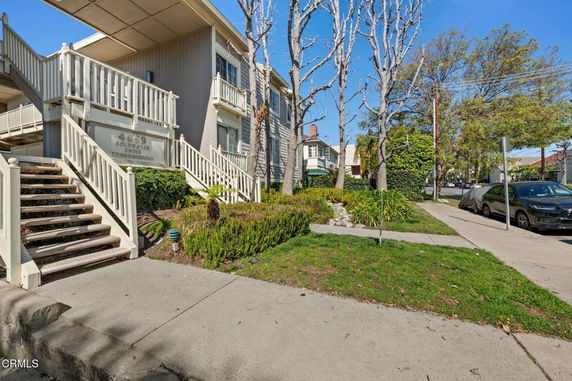 Front view of a two-story condominium building with stairs leading to the entrance.