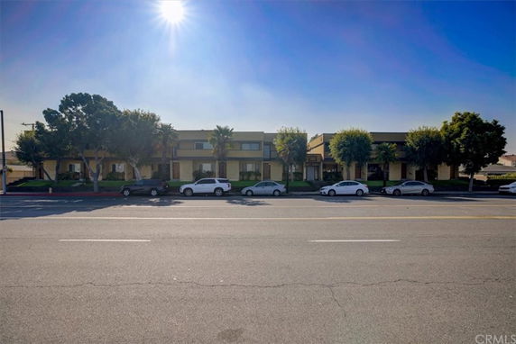 Front view of a two-story building with multiple units and parking in front.