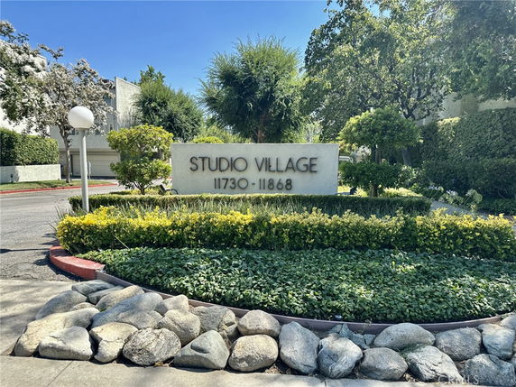 Front view of the Studio Village housing complex sign with surrounding greenery.
