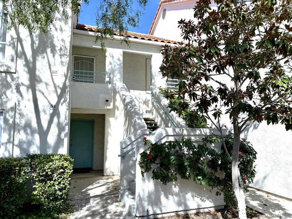 Front view of a two-story building with exterior stairs and greenery.